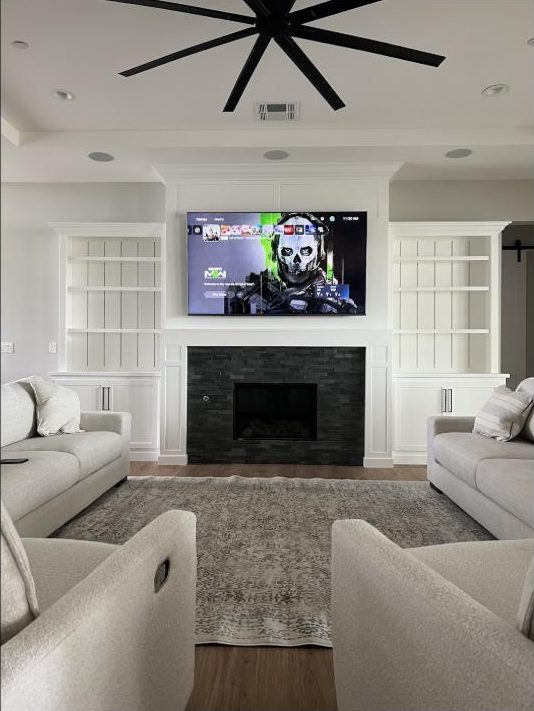 Gaming setup installed by Kalieb Designs with TV mounted over a stone fireplace and console equipment neatly integrated
